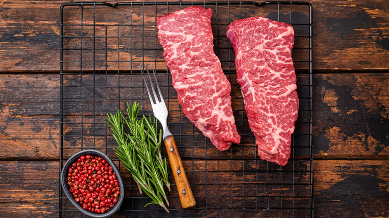 Raw shoulder tender cuts on wire rack with herbs
