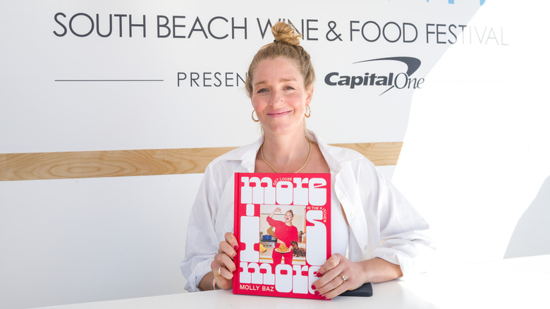 Molly Baz holding her own cookbook