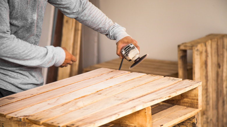 Person sanding a wood pallet
