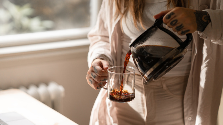 Person pouring coffee into a cup.