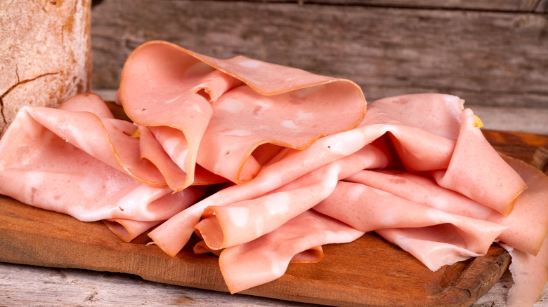 Thinly sliced Italian mortadella on wooden cutting board