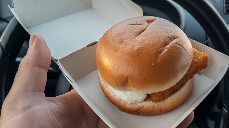 A person holding a McDonald's filet-o-fish still in the carton