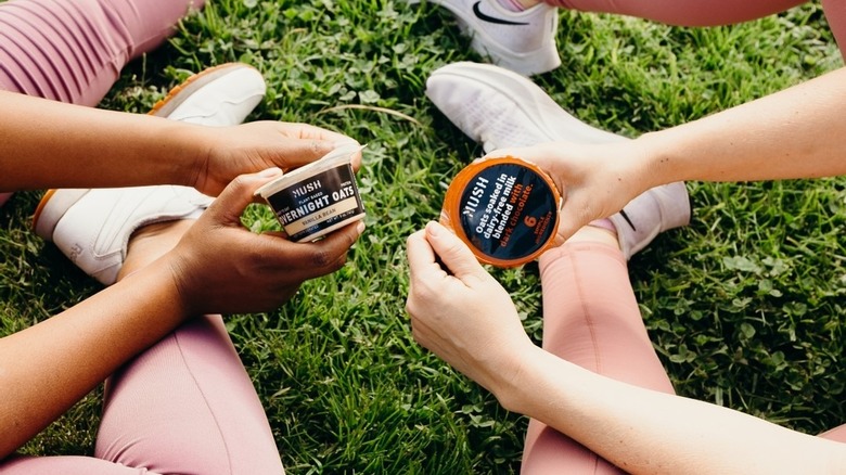 Two people stretching on grass holding MUSH oats