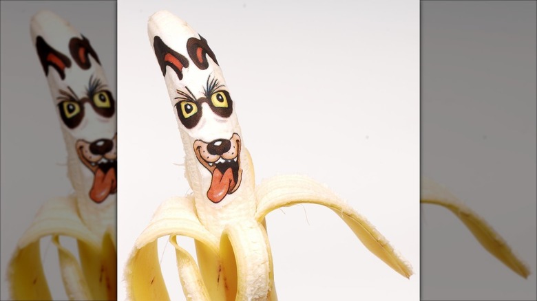 A half-peeled banana with an edible sticker of a dog face on it