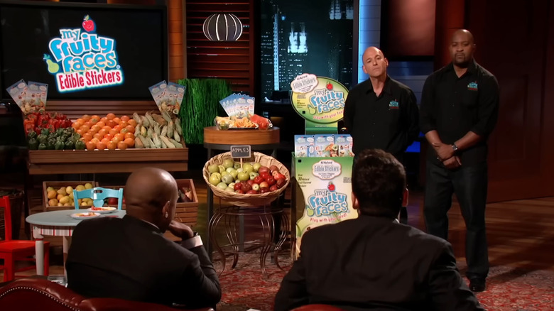The founders of My Fruity Faces stand next to their display of produce and edible stickers on Shark Tank