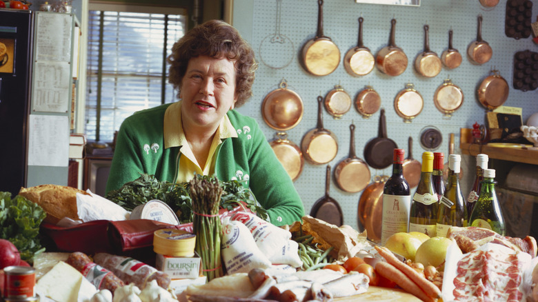 Julia Child in a kitchen surrounded by ingredients