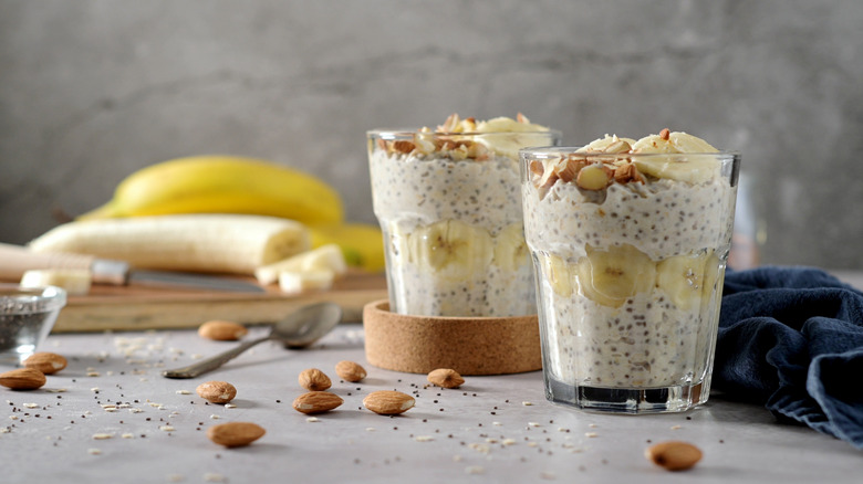 two jars of overnight oats with banana and almond scattered around
