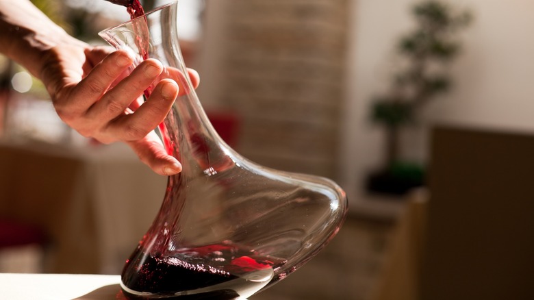 Hands pouring red wine into a decanter