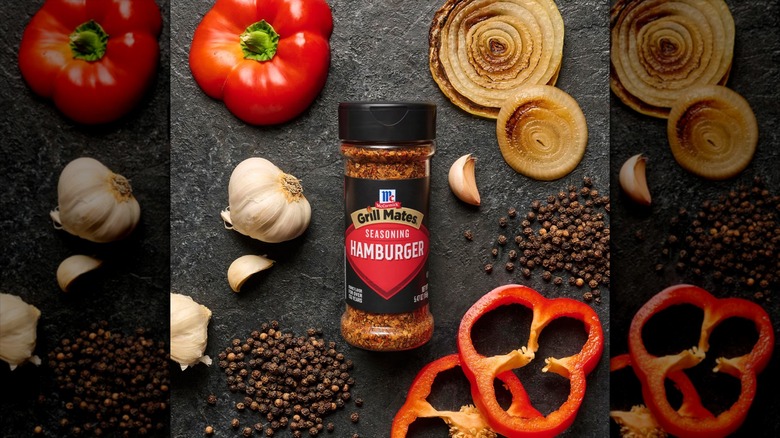 A bottle of McCormick Grill Mates Hamburger Seasoning is surrounded by vegetables and piles of peppercorns.