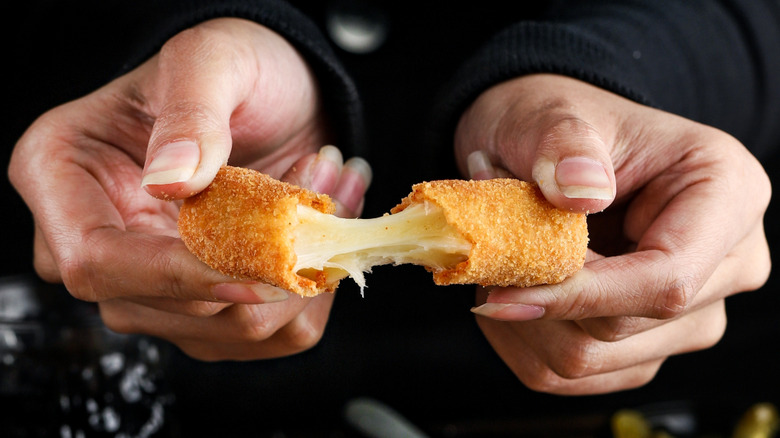 Two hands pull apart a mozzarella stick