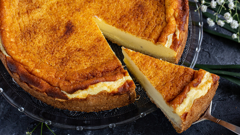 A slice of baked cheesecake being cut from the dessert