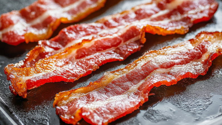A plate of freshly cooked bacon is covered in grease