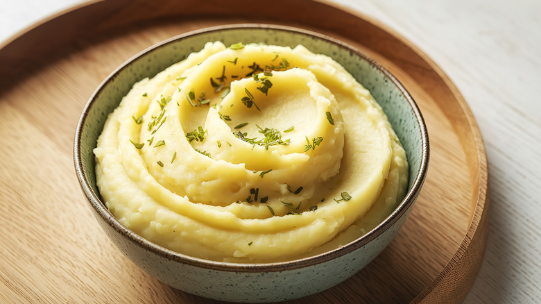 a bowl of mashed potatoes, topped with fresh herbs
