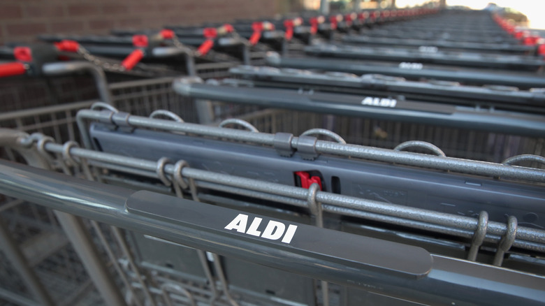 Aldi shopping carts sit lined up and connected to each other in a cart corral