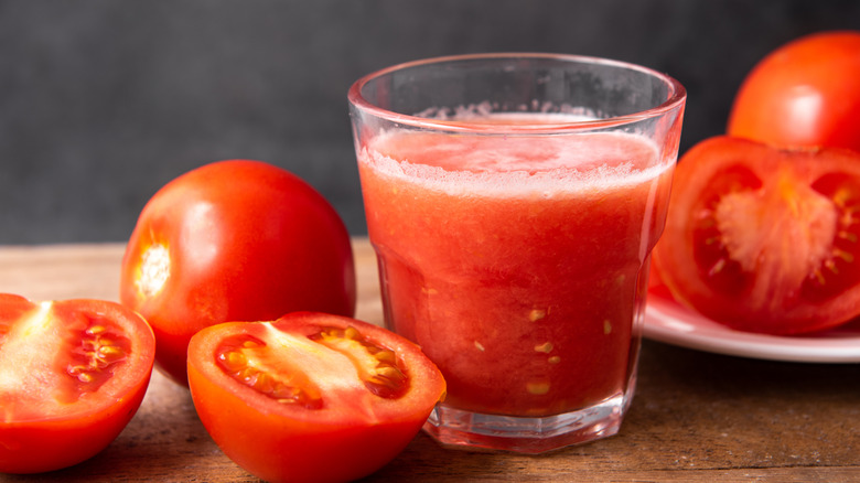 Tomato juice next to cut up tomatoes