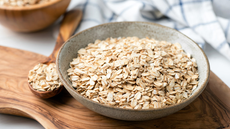 Dry oats in a bowl next to a spoonful of oats