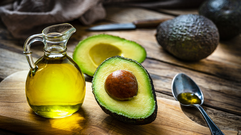 A bottle of avocado oil next to avocados.