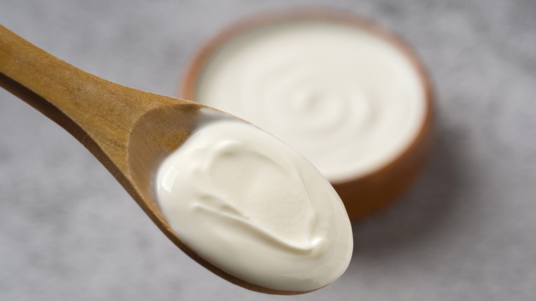 Yogurt is removed from a bowl with a wooden spoon.