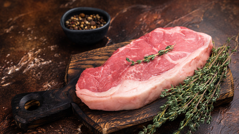 Raw New York strip beef steak, also named Striploin steak on a wooden board.