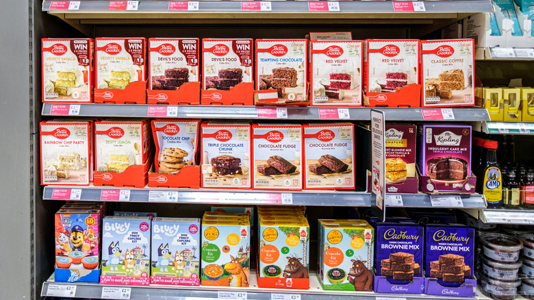 A baking section at a grocery store is decked out with cake mixes and premade frostings.