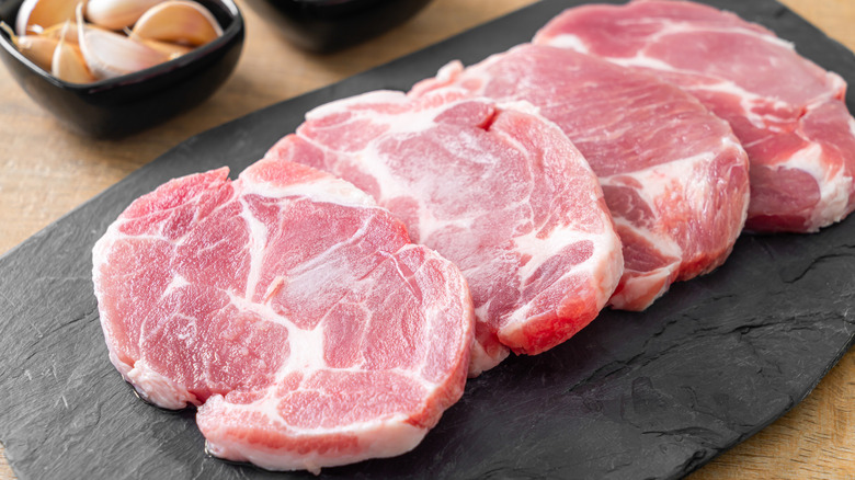 Several raw pork collar steaks.