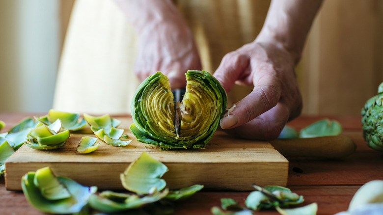 Close-up of hands cutting artichoke