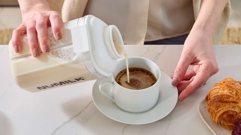 Consumer pouring Numilk into their coffee at a counter