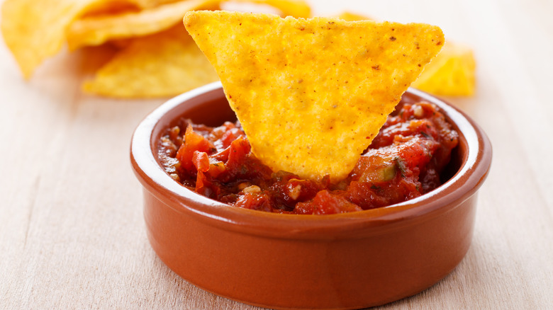 tortilla chip in bowl of jarred salsa