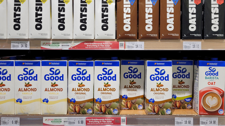 Store shelf showing oat milk and almond milk price tags