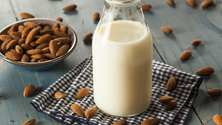 Almond milk in jug next to bowl of almonds