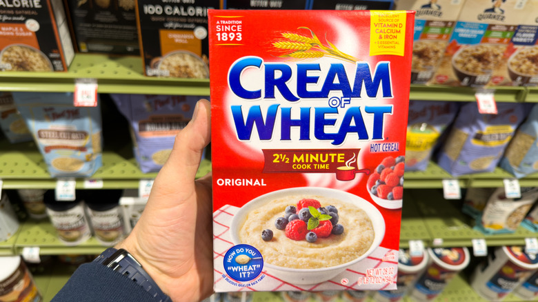 A hand holds of package of Cream of Wheat at the grocery store.