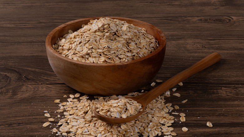 A bowl and wooden spoonful of raw oats.