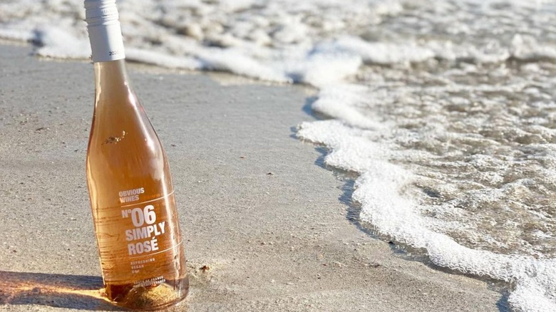 A bottle of Obvious Wines rose on a beach