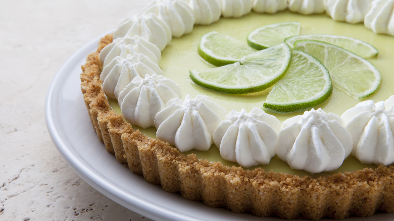 key lime pie on a plate with lime wedges on top
