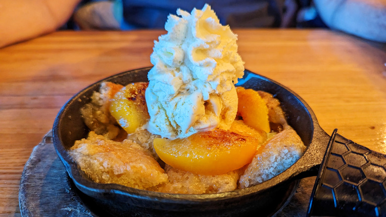 peach cobbler with whipped topping in a pan