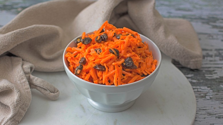 Shredded carrots and raisins in a white bowl