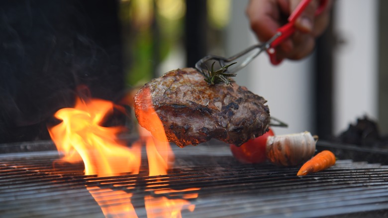 Chef turning meat on an outdoor grill