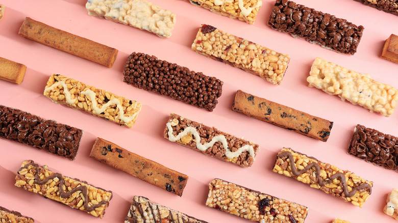 An array of energy bar varieties arranged neatly before a pink background