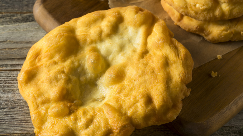 Golden fry bread resting on wooden board and table