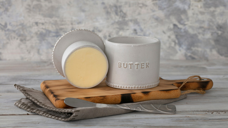 Butter crock on a wood board next to knife