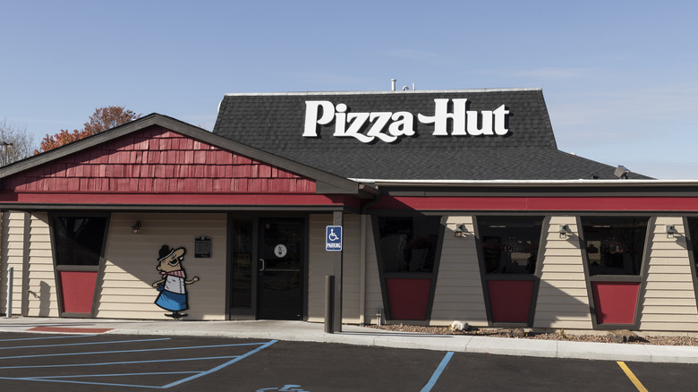 Exterior of a Pizza Hut with two-toned roof and light-colored siding