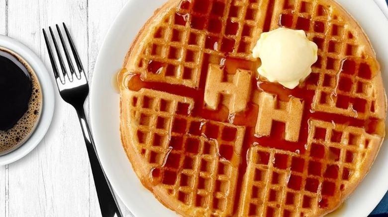 Waffle with "HH" in the center for Huddle House with a small butter scoop and syrup