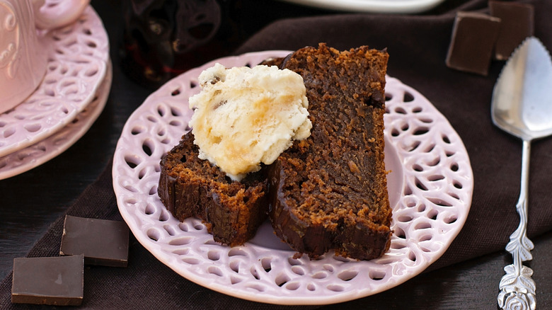 Sliced cola cake topped with ice cream on a pink plate