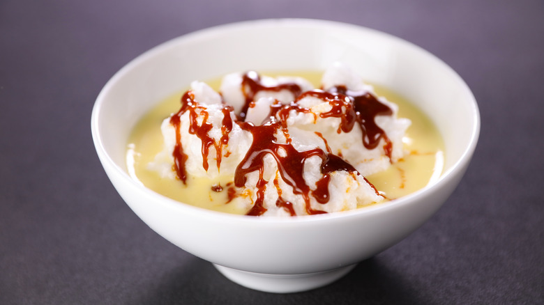 The dessert floating island featured in a white bowl drizzled with caramel