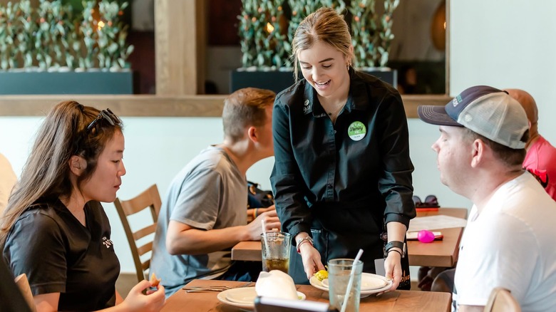 A server at Olive Garden helping two diners at their table.