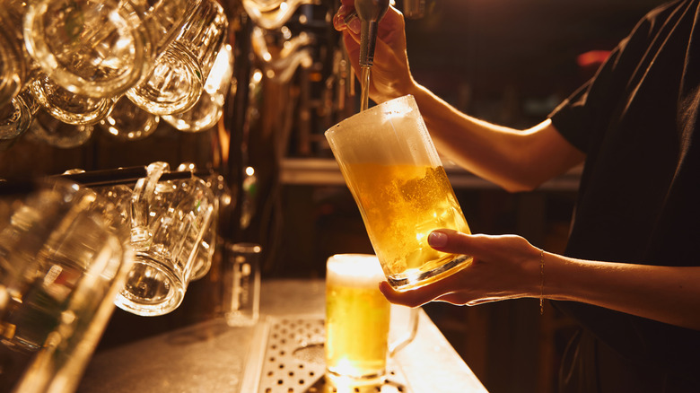 Bartender pouring beer from a tap into a large glass mug