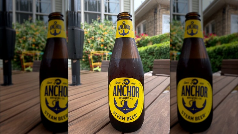 A bottle of Anchor Steam beer on a table in a garden