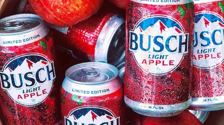 Cans of Busch Light Apple with water on them, in a basket of apples