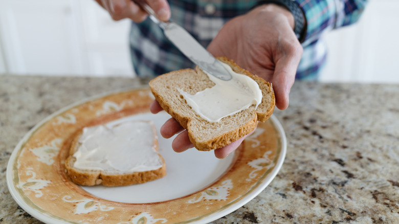 Man spreading mayo on a piece of bread