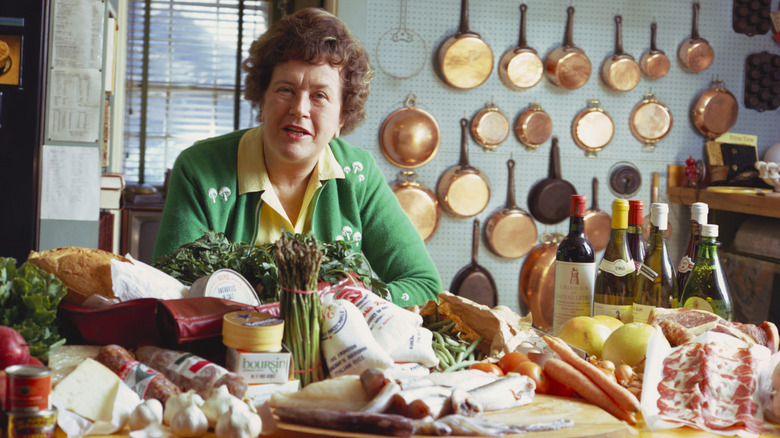 Julia Child in her kitchen with a wide variety of resh produdce and meats